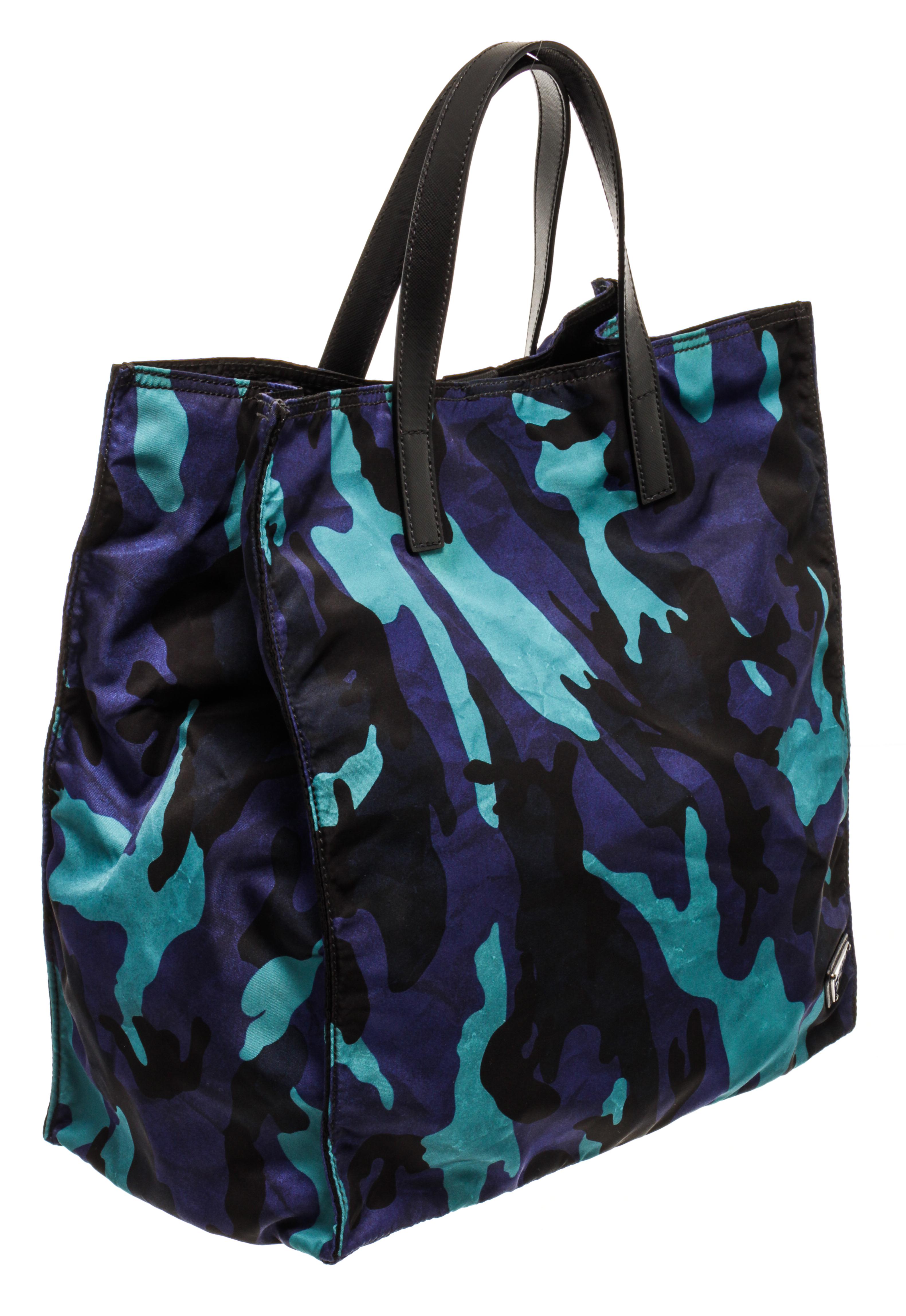 Prada blue camo nylon tote bag with top handles, snap button closure, black nylon lining, and one interior zip pocket.

83276MSC
