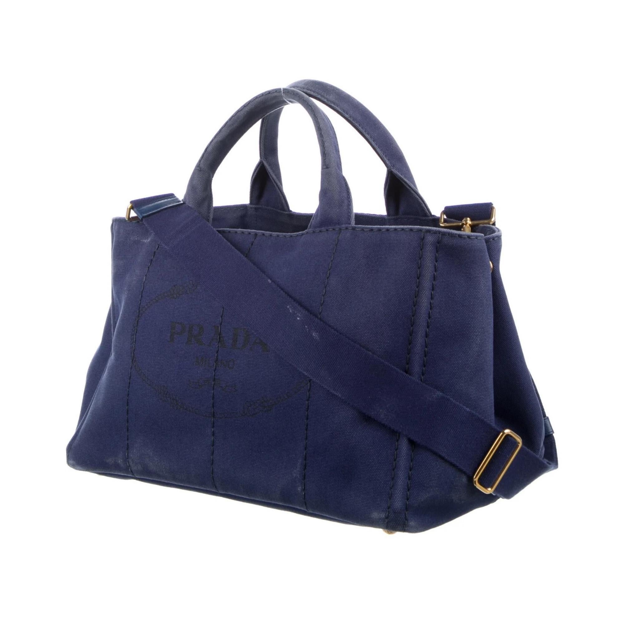 Prada Tote. From the 2015 Collection. Bauletto. Gold-Tone Hardware. Flat Handles. Canvas Lining & Five Interior Pockets. Open Top. Protective Feet at Base.

COLOR: Blue
MATERIAL: Canvas
ITEM CODE: 203
REFERENCE CODE: 1BG642
MEASURES: H 8.5” x W