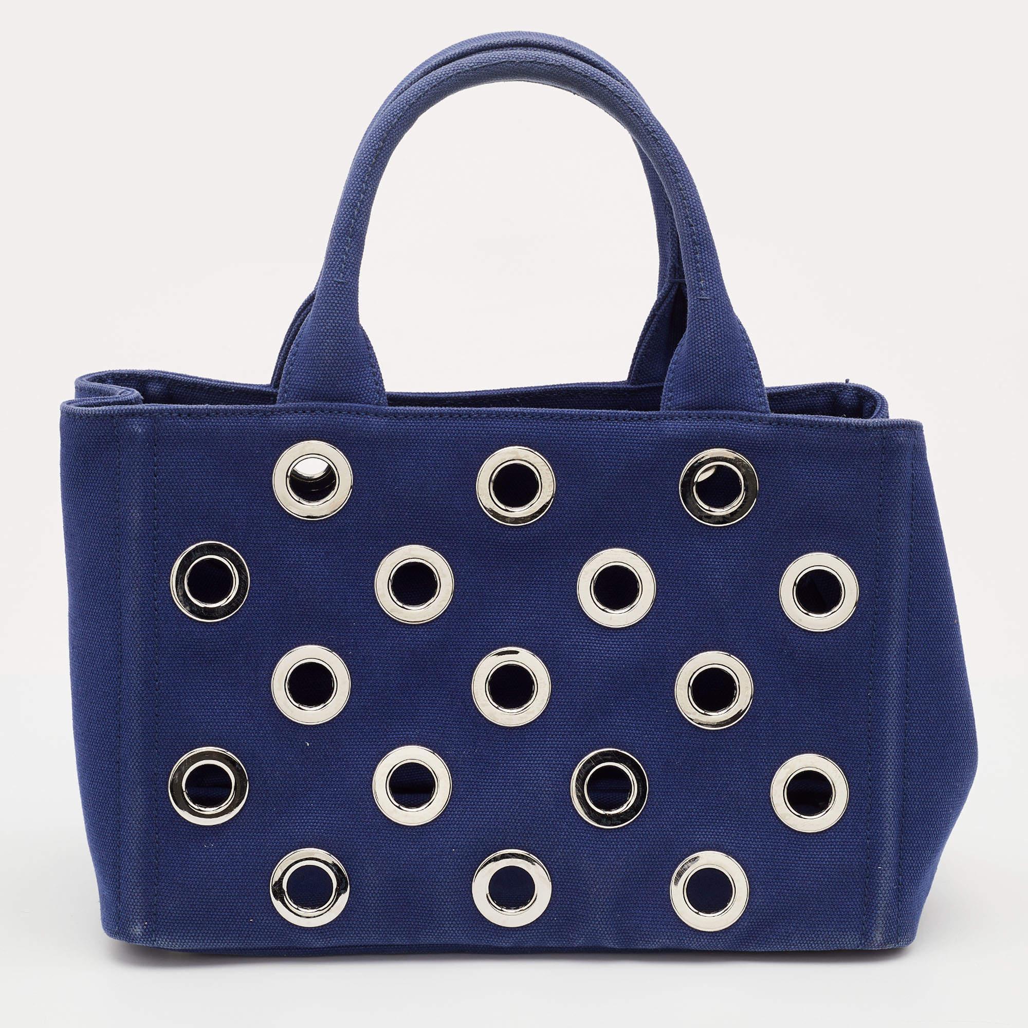 One of the most iconic designs from the house of Prada, this canvas Canapa tote bag is great to wear through the day or at your vacations and never compromise of style. Crafted in blue canvas fabric, this bag features the logo at the front face