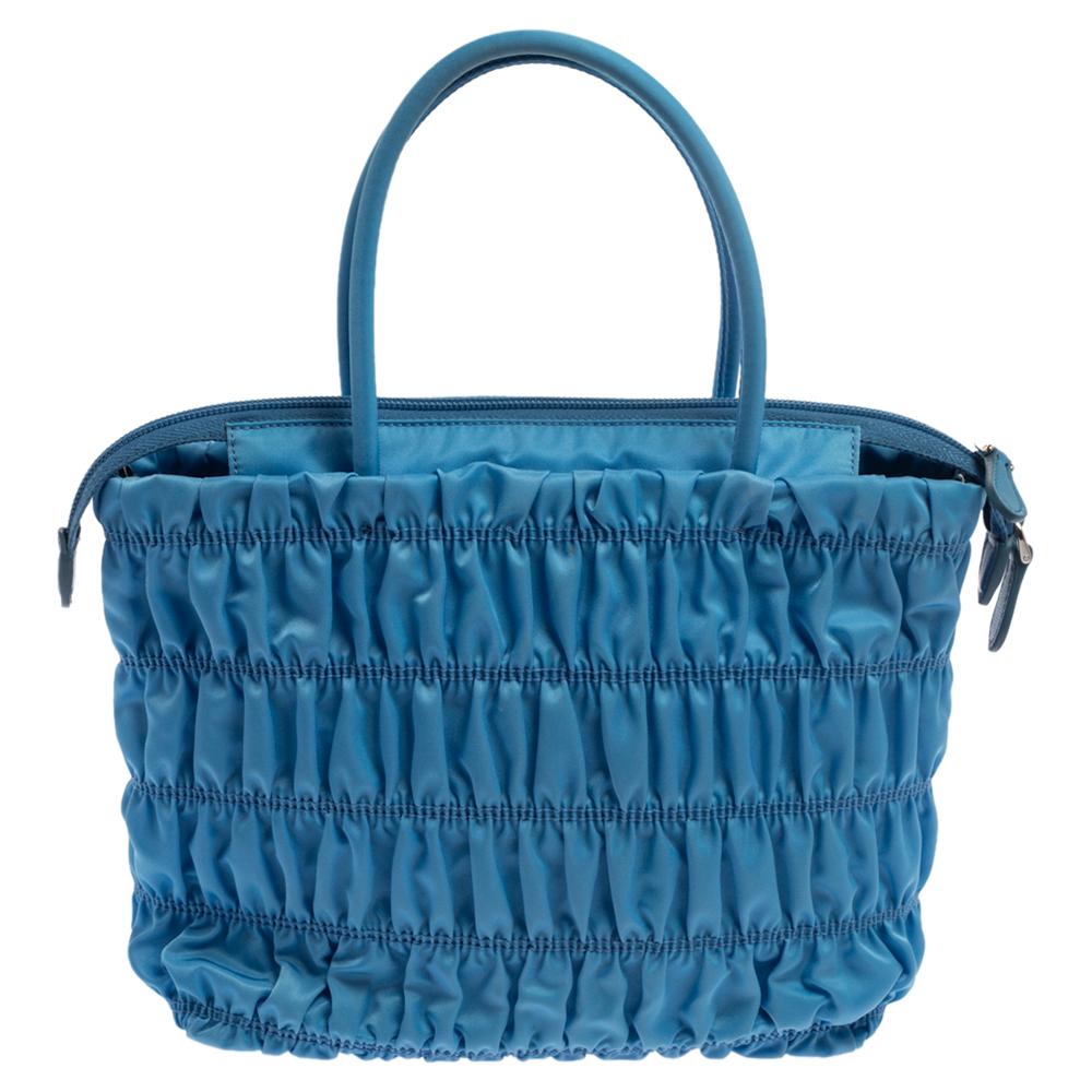 Prada brings to you this pretty bag. Complemented with a classic blue hue all over, this tote is all you need to flaunt your style this season. it has been crafted from embossed nylon and comes with dual handles, a silver-tone logo in the front, and