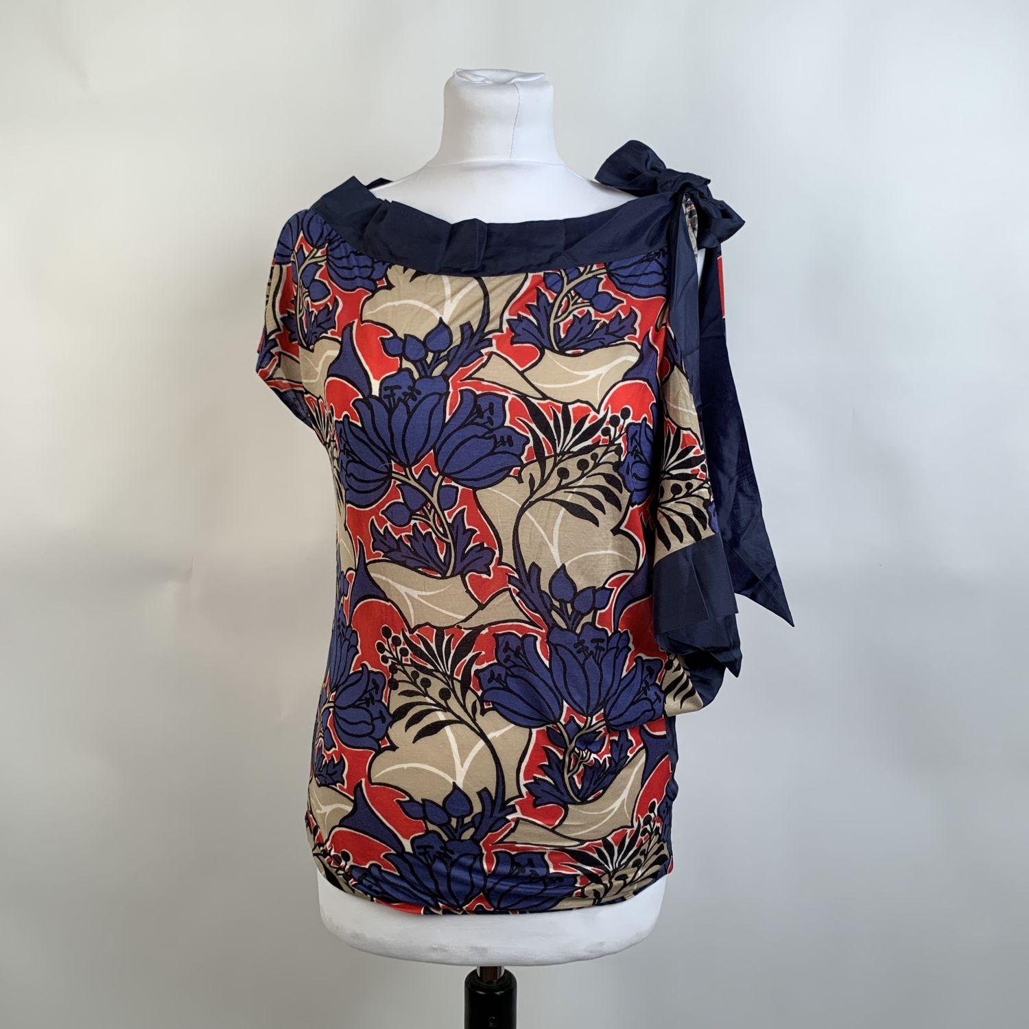 Prada top t-shirt with floral dsign in blue, red and beige color. It features boat neckline, an asymmetric design, hadkerchief detailing on the right side and bow detailing on the shoulder. Composition tag is missing. it seems to be cotton jersey