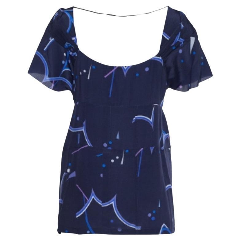 Questa blusa di Prada aggiungerà la giusta quantità di colore al tuo look. Realizzata in tessuto di seta Fabrice de Chine con stampa geometrica blu, presenta maniche corte e chiusura con cerniera. Aggiungi questa camicetta al tuo guardaroba per un