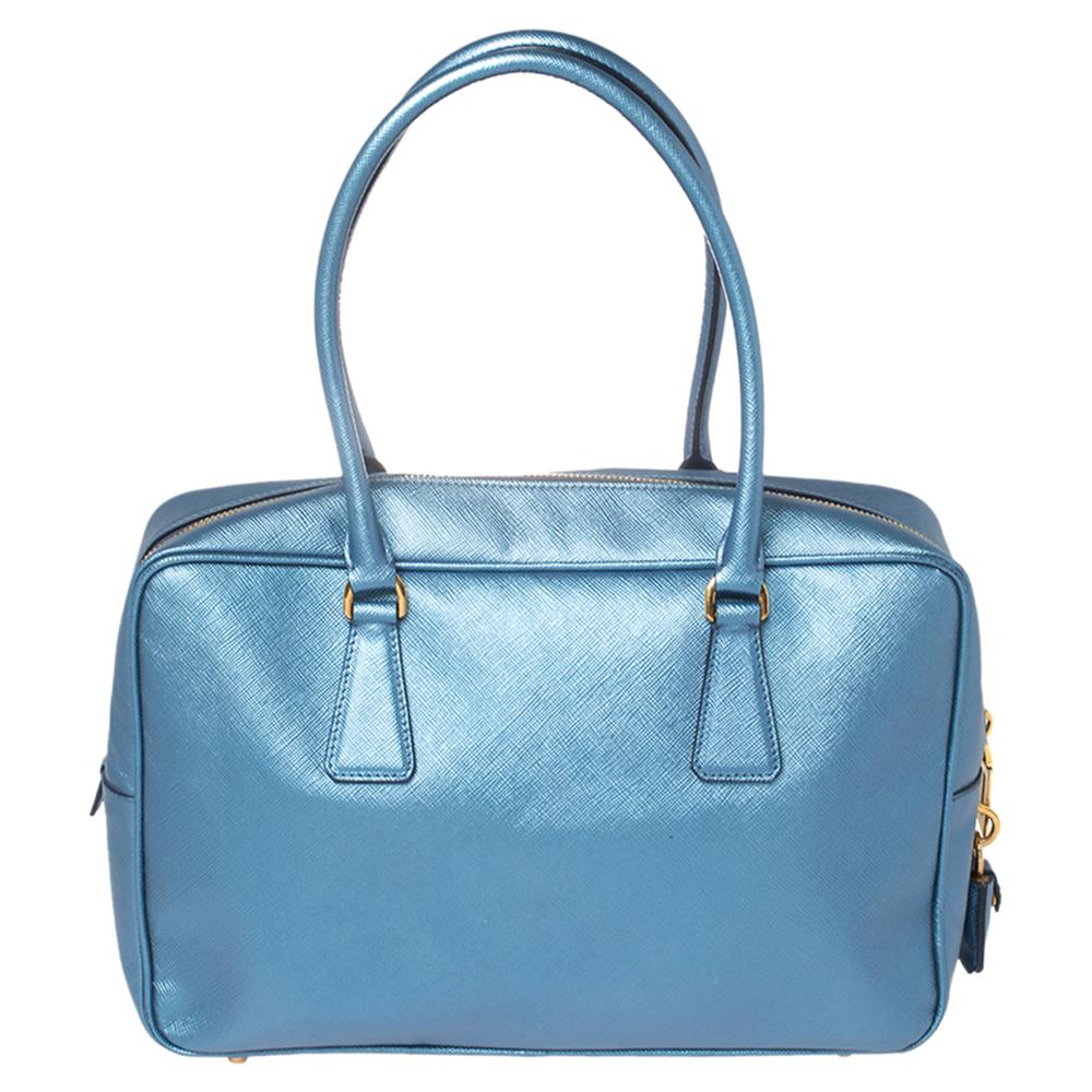 The Prada Bauletto bag is spacious and stylish. It will give you all the space you need. It features a leather exterior, dual-leather rolled handles, the Prada insignia on the front, and gold-tone hardware. The nylon-lined interior has one zip