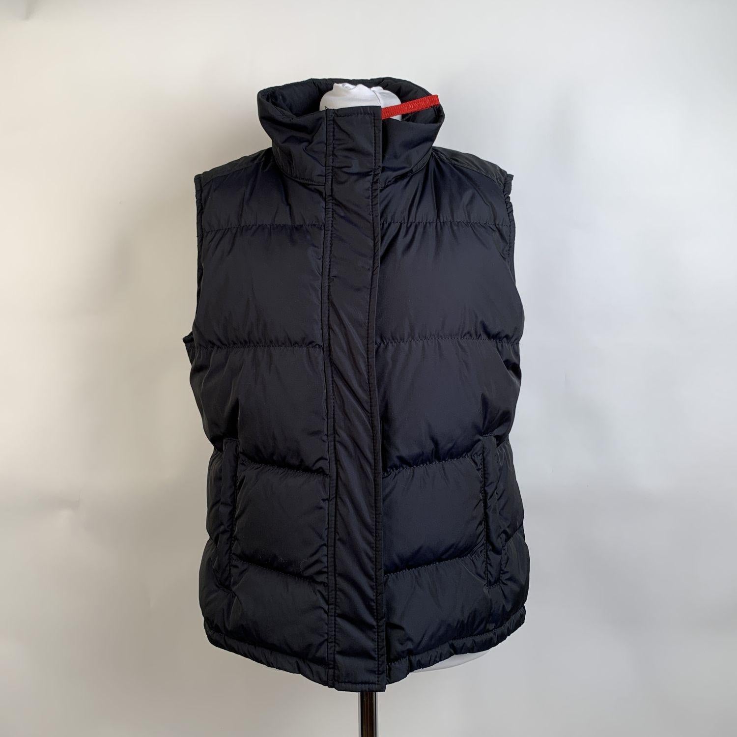 PRADA sleeveless down jacket. Constructed in navy blue nylon with a quilted pattern. Down feather padding. It features a high neck with concealed hood, a zipper closure down the front and 2 zippered pockets. Inner pockets. Size: 46 IT (The size