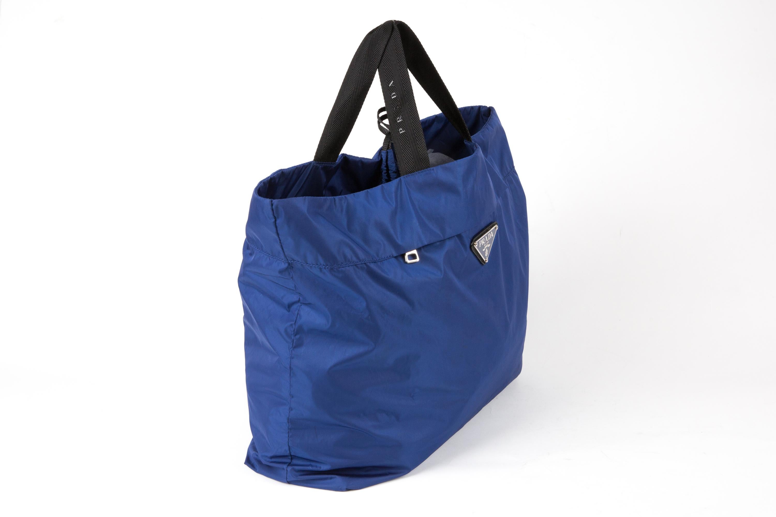 Prada Blue nylon Tessuto folding totebag featuring the enameled metal triangle logo on the front, top black logo handles, an inside compartment with top zipper closure, an interior inside compartment with top zipper and a separated blue nylon