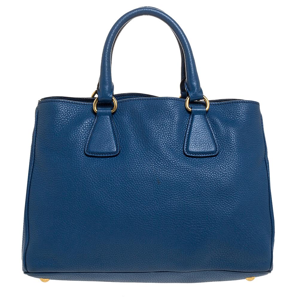 This Prada leather tote is a fine handbag to get your hands on. It is made from blue pebbled Vitello Daino leather with the brand logo on the front. It features top handles and protective feet. The tote has a spacious nylon-lined
