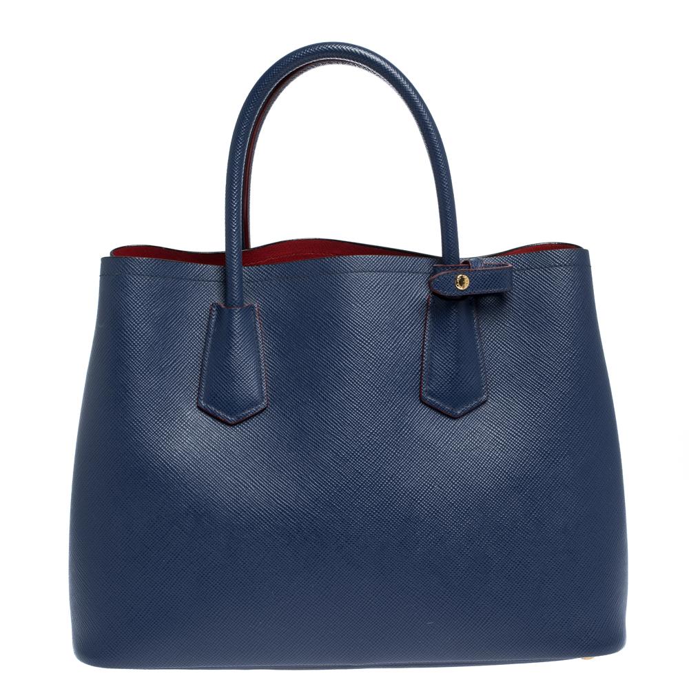 This lovely tote from Prada is crafted from Saffiano Cuir leather and features a blue shade. It flaunts dual handles, brand logo, protective metal feet, and a spacious leather-lined interior with enough space to house all your belongings. It is