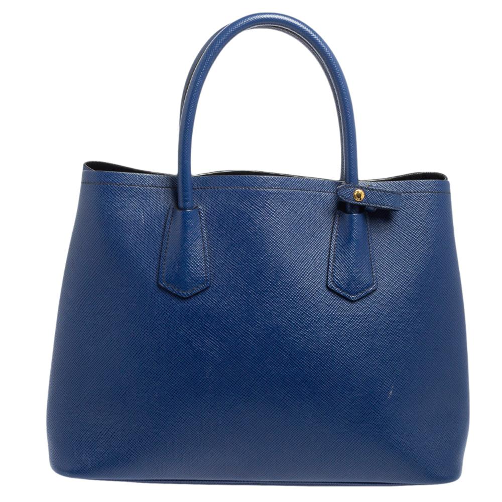 This lovely tote from Prada is crafted from Saffiano Cuir leather and features a blue shade. It flaunts dual round handles, an attached tag, protective metal feet, and a spacious leather-lined interior. Perfect to complement most of your outfits,