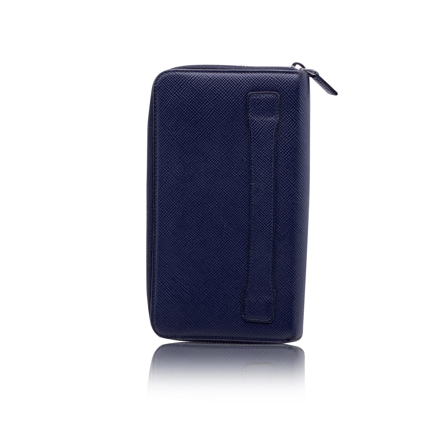 Prada travel organizer wallet in blue 'Saffiano' leather. Silver metal PRADA triangle logo on a corner. Double zip compartment. 3 open pockets, 14 credit card slots in a compartment. 2 bill sections, 2 open pockets, 1 middle zip compartment and 12