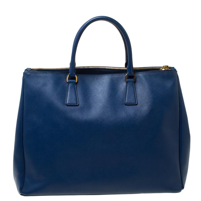 Feminine in shape and grand on design, this Executive Double Zip tote by Prada will be a loved addition to your closet. It has been crafted from Saffiano leather and styled minimally with gold-tone hardware. It comes with two top handles, two zip