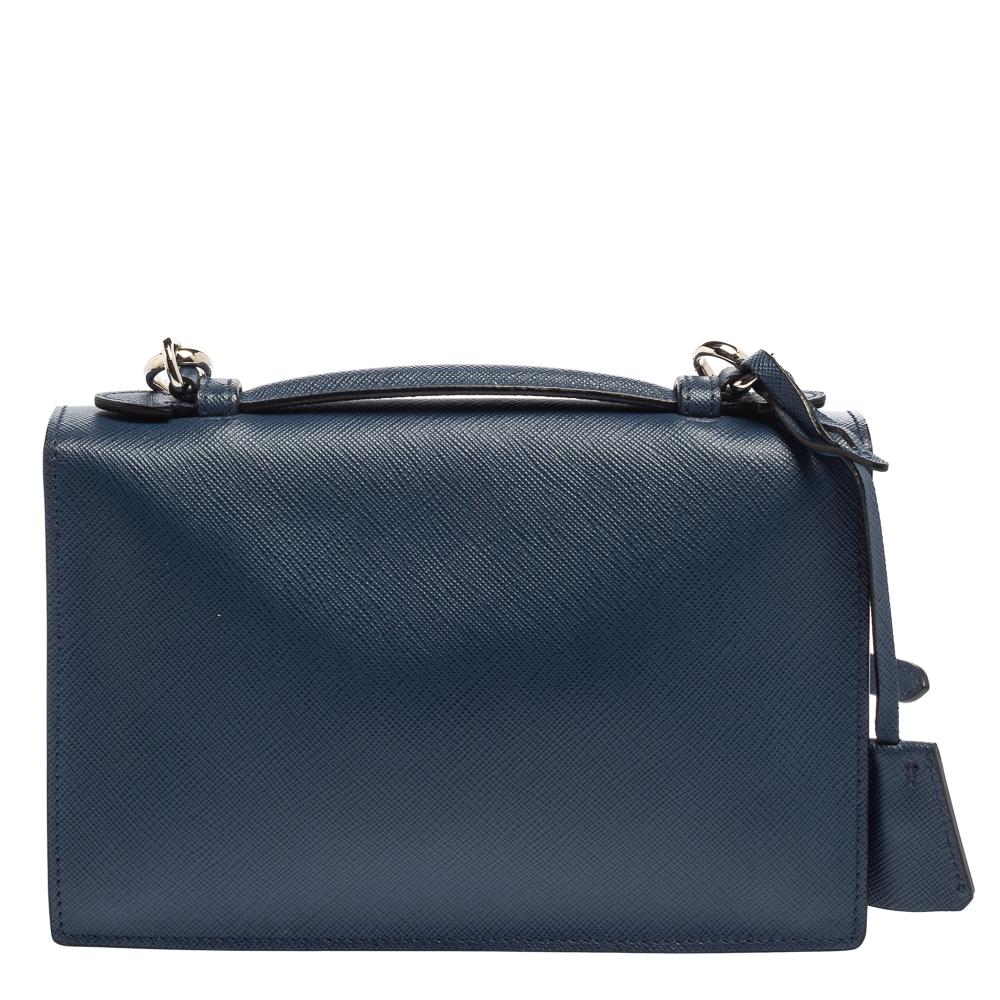 Perfect to compliment your incredible sense of style, this blue bag from Prada is a creation that epitomizes excellent craftsmanship. It has been brought to life using Saffiano leather and styled with a front flap that carries a silver-tone lock. It