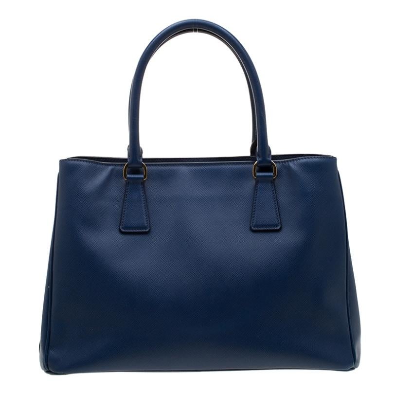 Prada introduces a creation that is chic enough to use for your daily use and yet still look perfect. This small tote is crafted with saffiano leather with double handles for your utmost comfort. The open top of the bag leads to interiors with a