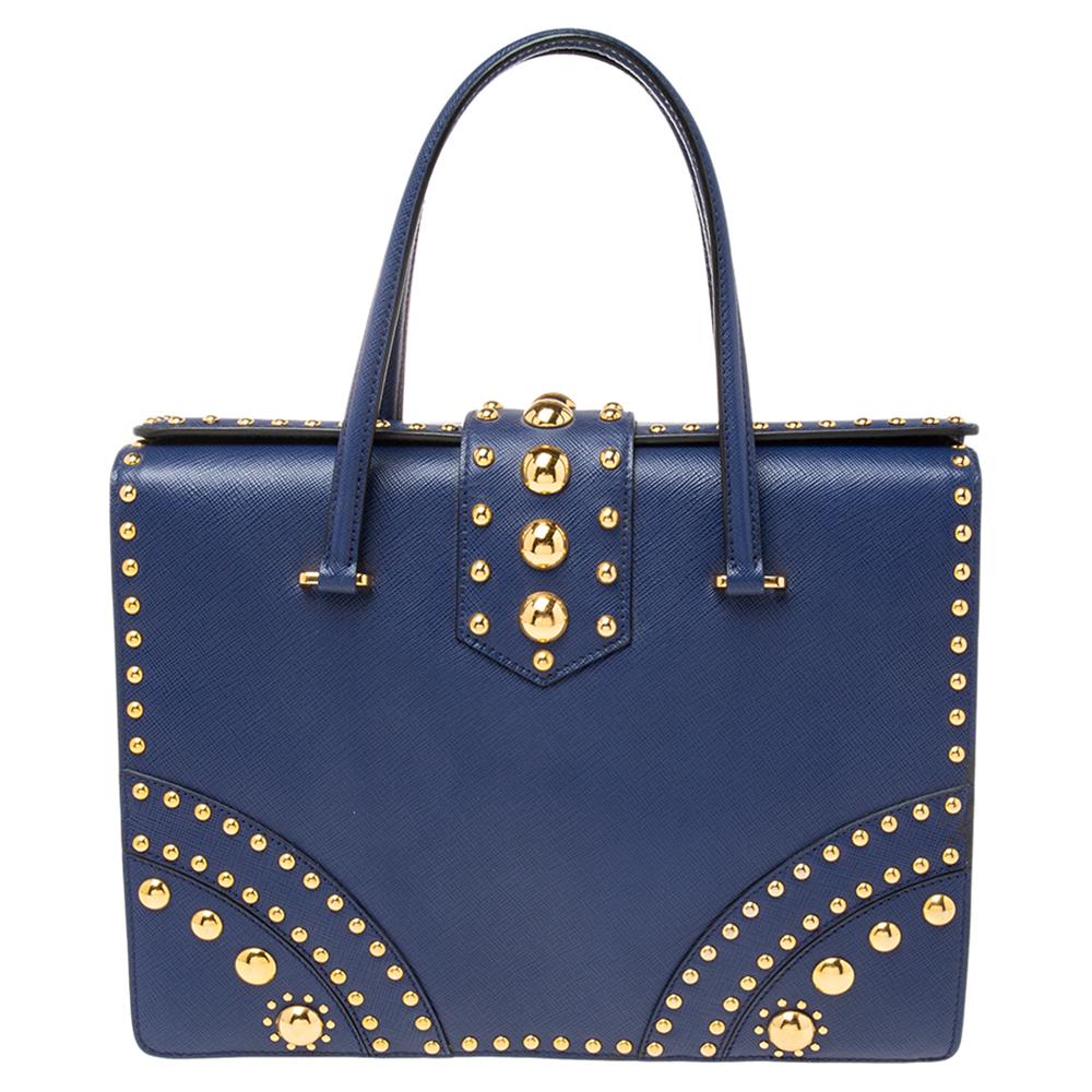 Upgrade your handbag collection with this super-chic bag that is beautifully studded. The blue-colored piece is made from Saffiano leather and flaunts striking gold-tone hardware. It has a structured shape and a capacious interior for your essential