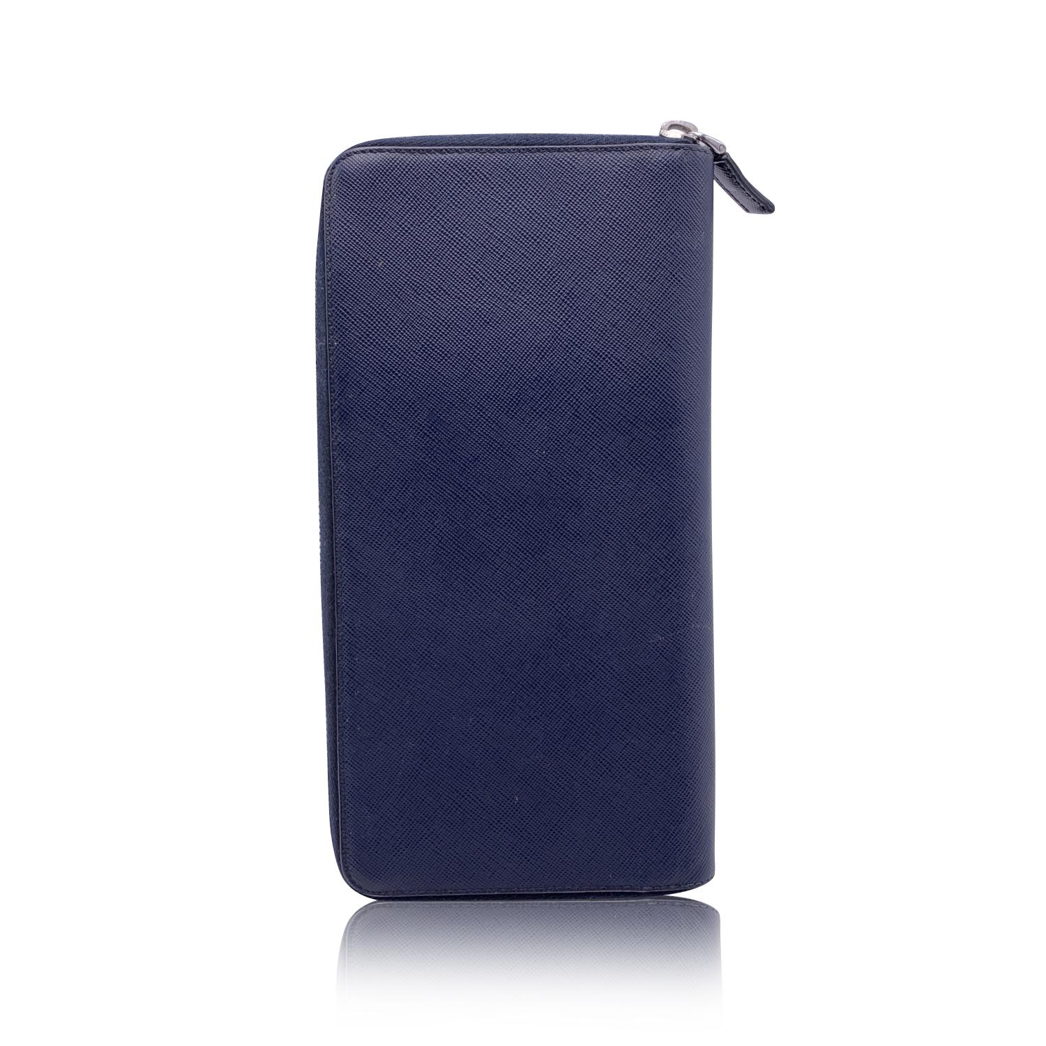 Prada travel wallet in blue 'Saffiano' leather. Silver metal PRADA logo lettering. Wrap-around zipper. 1 bill compartments & 1 middle zip compartment for coins. 17 credit card slots & 1 open pocket inside. 'Prada - Milano' engraved on leather