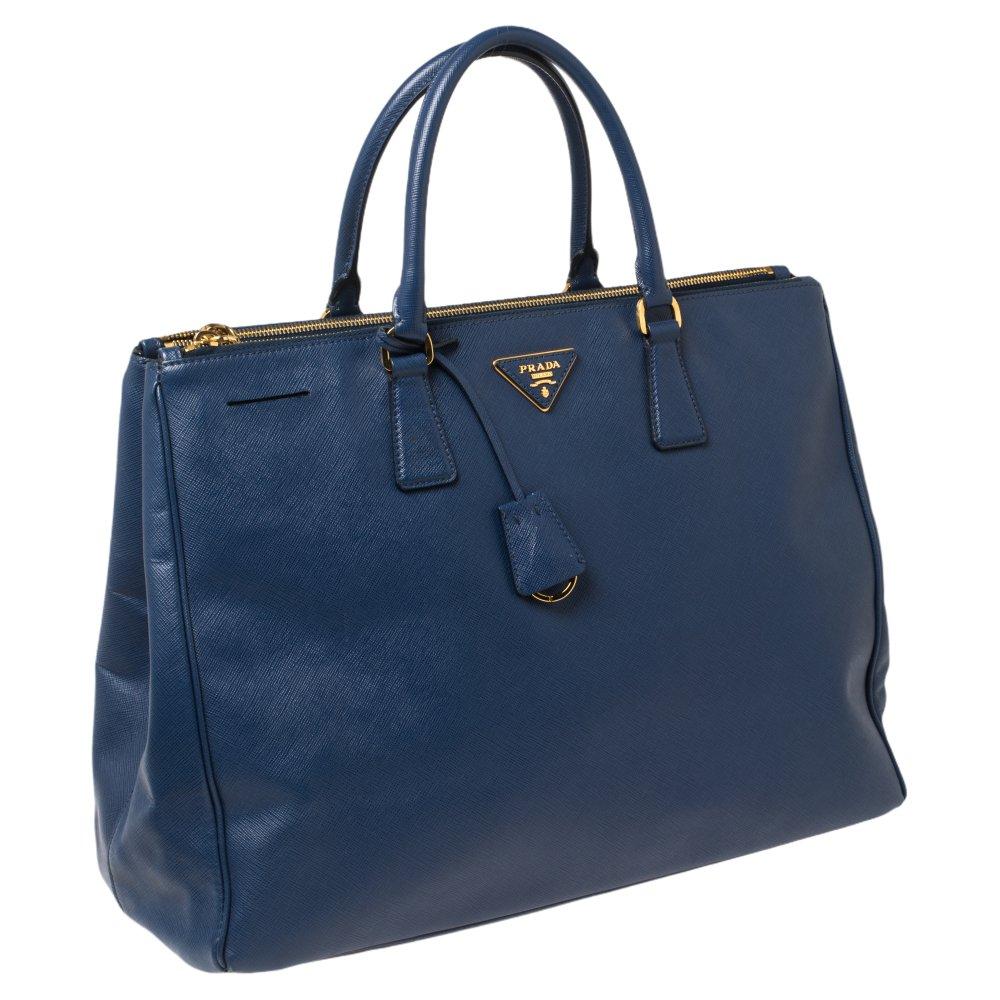 This Galleria tote is one of the most iconic bags from the house of Prada. This beauty in blue is crafted from Saffiano leather and is equipped with two top handles, the brand logo at the front, and gold-tone hardware. With an ultra-spacious