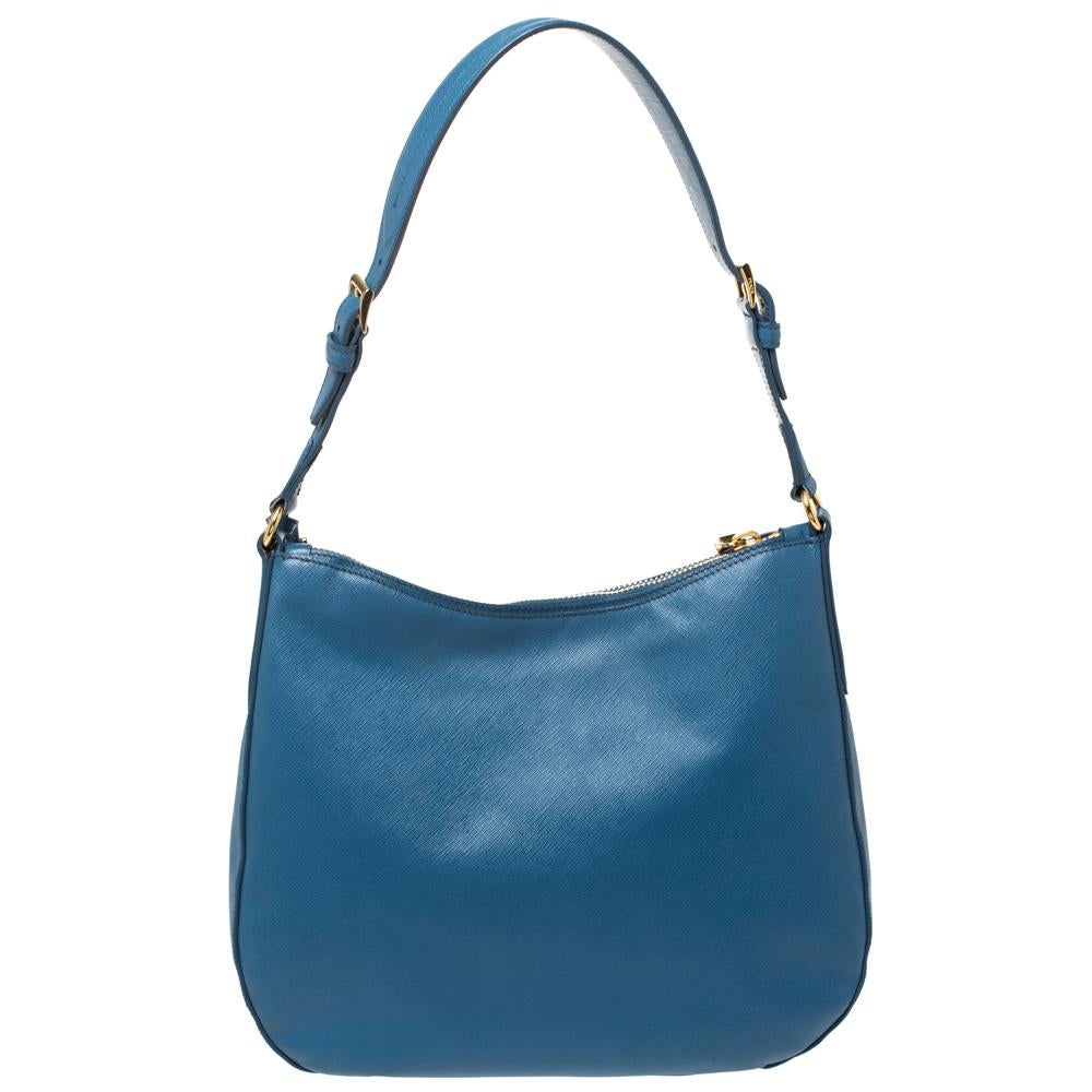 Diese Prada-Hobo-Tasche ist für ihre exklusive Handwerkskunst bekannt und wird Ihre Erwartungen erfüllen. Sie ist aus Saffiano Lux-Leder gefertigt und in einem klassischen Schwarz gehalten. Das Innere der Tasche besteht aus Nylon und bietet Platz