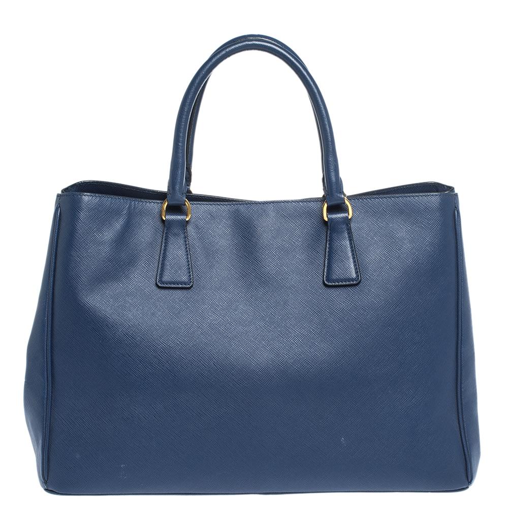 High in appeal and style, this tote is a Prada creation. It has been crafted from Saffiano Lux leather and shaped to exude class and luxury. The blue bag comes with two handles and a spacious nylon interior for your ease. Protective metal feet and