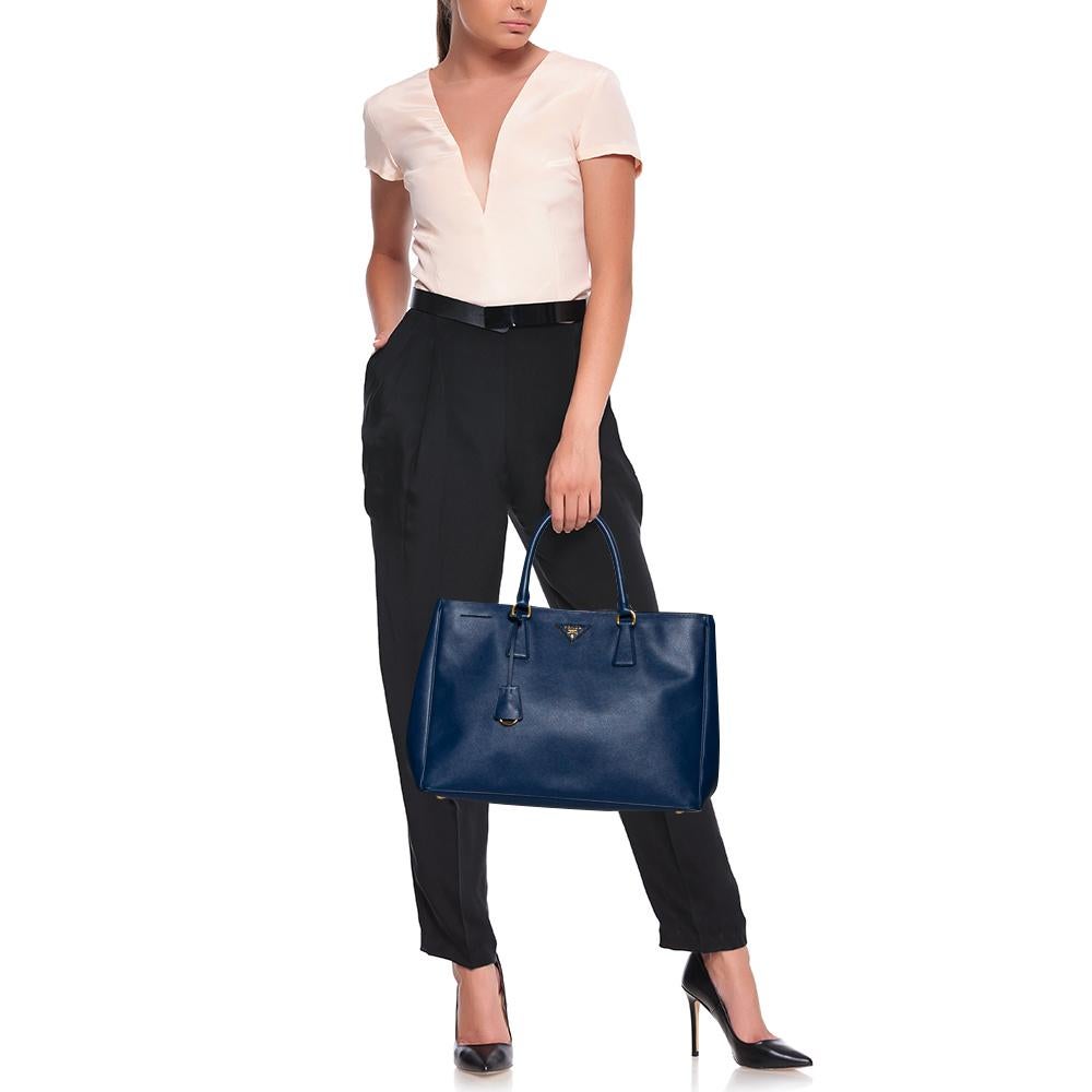 High in appeal and style, this tote is a Prada creation. It has been crafted from leather and shaped to exude class and luxury. The bag comes with two handles and a spacious nylon interior for your ease. Protective metal feet and the brand logo on