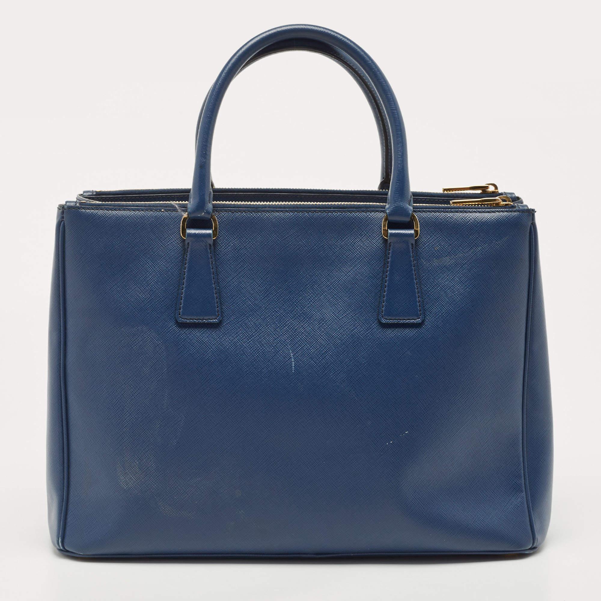 Feminine in shape and grand in design, this Double Zip tote by Prada will be a valuable addition to your closet. It has been crafted from Saffiano lux leather and styled minimally with gold-tone hardware. It comes with dual handles at the top, two