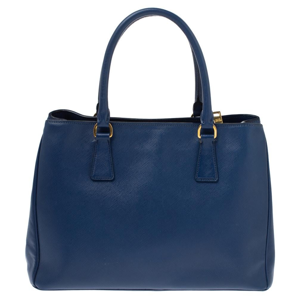 Loved for its classic appeal and functional design, Galleria is one of the most iconic and popular bags from the house of Prada. This beauty in blue is crafted from Saffiano Lux leather and is equipped with two top handles, the brand logo at the