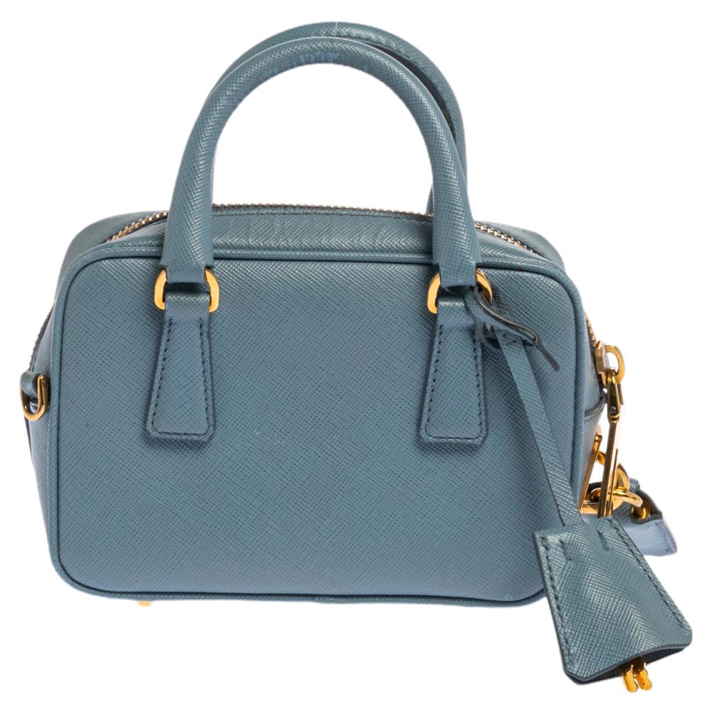 Prada's sized-down Bauletto beautifully balances an adorable silhouette with the brand's high level of artisanship. Pretty in blue, the Mini Bauletto Prada bag in Saffiano Lux leather is attached with two handles and an optional shoulder strap.