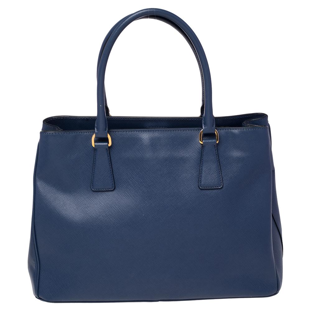 Feminine in shape and grand in design, this tote by Prada will be a loved addition to your closet. It has been crafted from Saffiano Lux leather and styled minimally with gold-tone hardware. It comes with two top handles and a nylon-lined interior