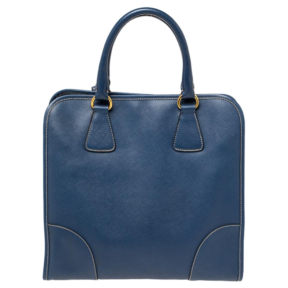 Feminine in shape and grand in design, this tote by Prada will be a loved addition to your closet. It has been crafted using Saffiano Lux leather and styled minimally with gold-tone hardware. It comes with two top handles, nylon-lined compartments,