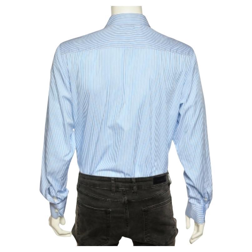 Cette chemise de la maison Prada garantit que votre ensemble formel est impeccable et positivement pointu. Il est taillé dans un coton rayé bleu et présente un devant boutonné, des poignets boutonnés et des manches longues. Associez cette chemise à