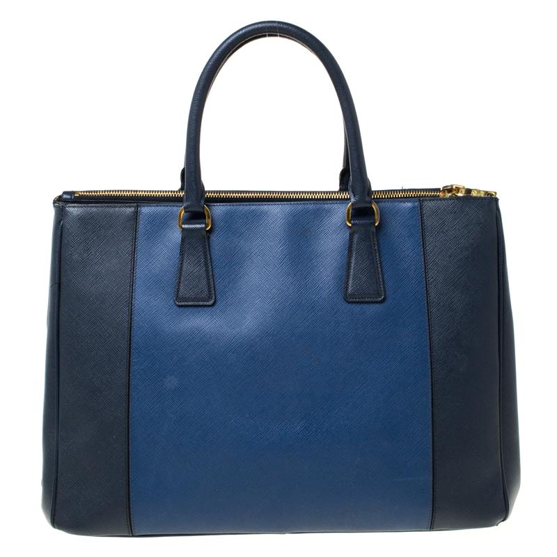 Feminine in shape and grand on design, this Double Zip tote by Prada will be a loved addition to your closet. It has been crafted from two-toned Saffiano Lux leather and styled minimally with gold-tone hardware. It comes with two top handles, two