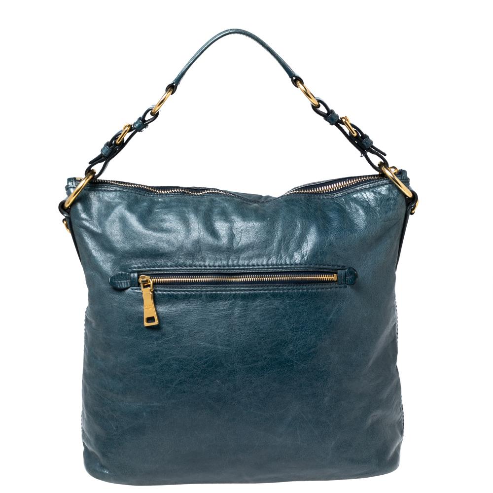 With this superb tote from the House of Prada, you will be able to carry your everyday belongings with ease and style. It is crafted using blue Vitello Shine leather on the exterior. It showcases gold-tone hardware, a fabric-lined interior, and a 20