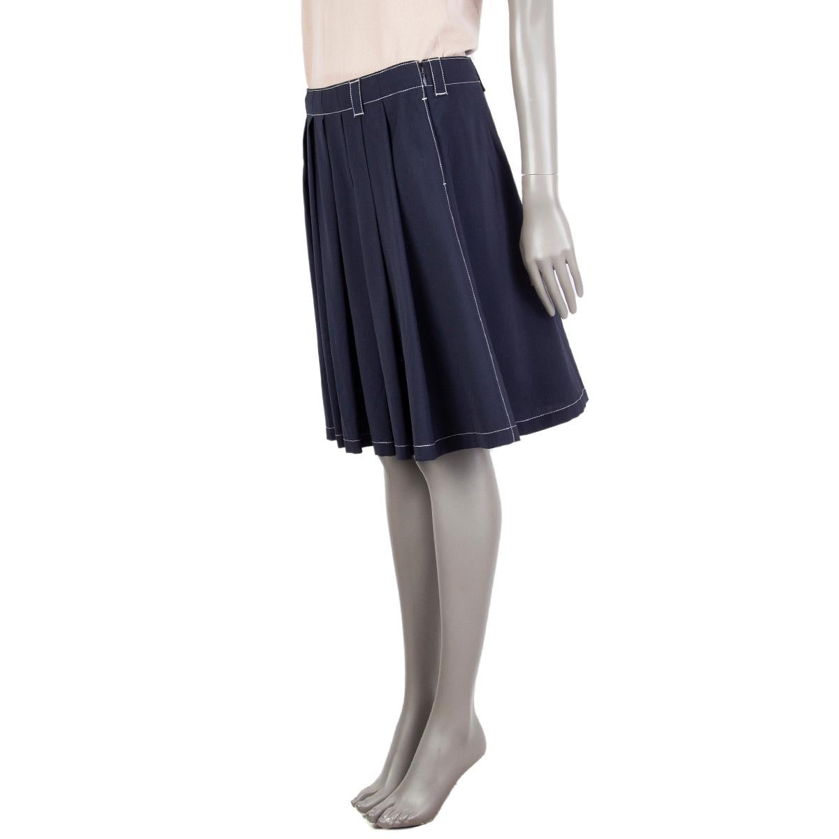 Prada white-stitched front-pleated skirt in midnight blue virgin wool (100%). Has one back pocket and two side pockets. Closes on the side with a concealed zipper. Peplum lining in cupro (100%). Has two hardly noticeable holes around the waitsline,