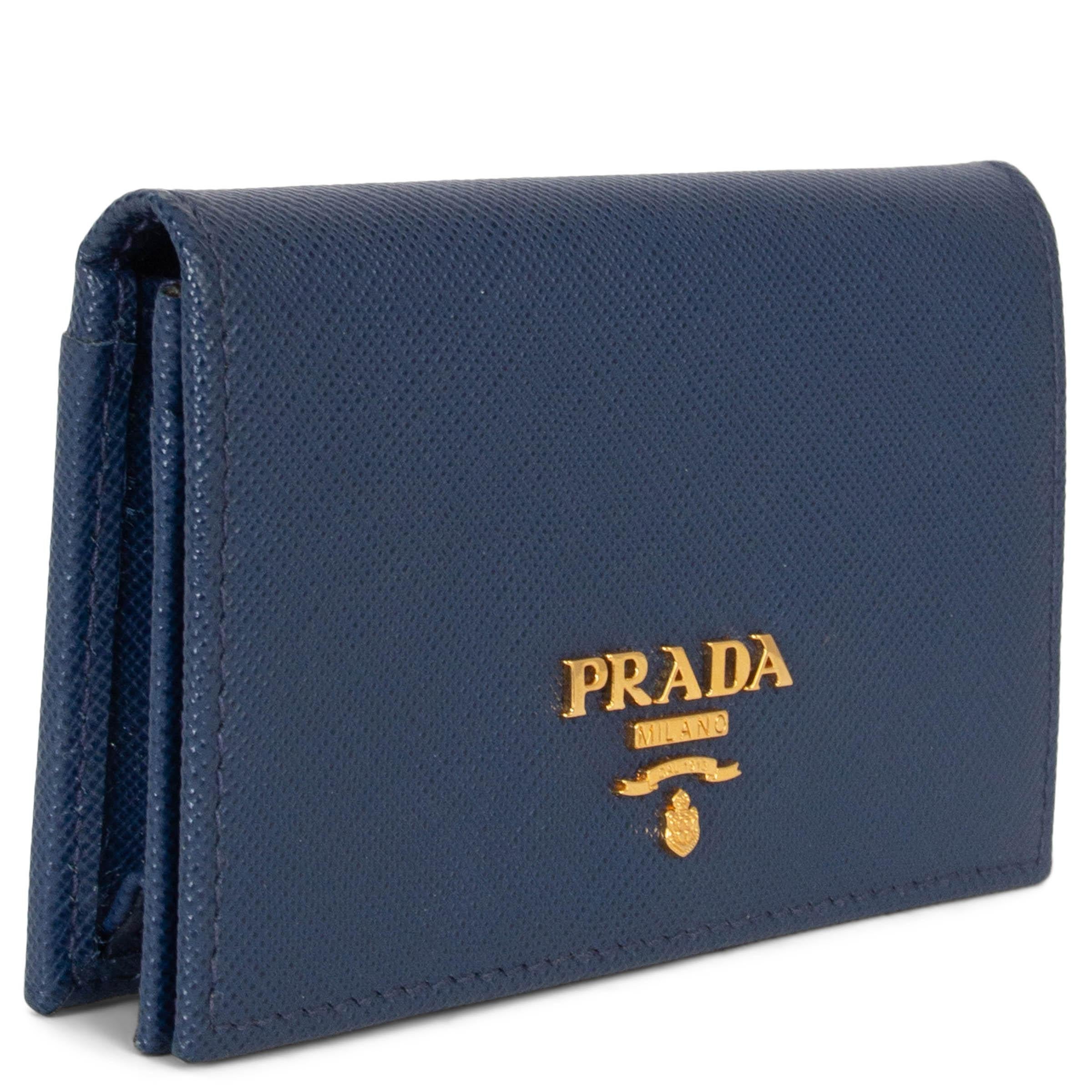 This 100% authentic Prada logo-plaque foldover cardholder embodies timeless Italian elegance and expert craftsmanship. Crafted from premium navy blue Saffiano calf leather, this sophisticated piece features a sleek foldover design with a gold-tone