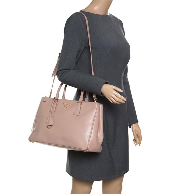 For women with an on-the-go lifestyle, this Double Zip tote from the house of Prada is an elegant option. Masterfully designed, it is rendered in blush pink Saffiano Lux leather and adorned with gold-tone hardware. The bag opens to an interior lined