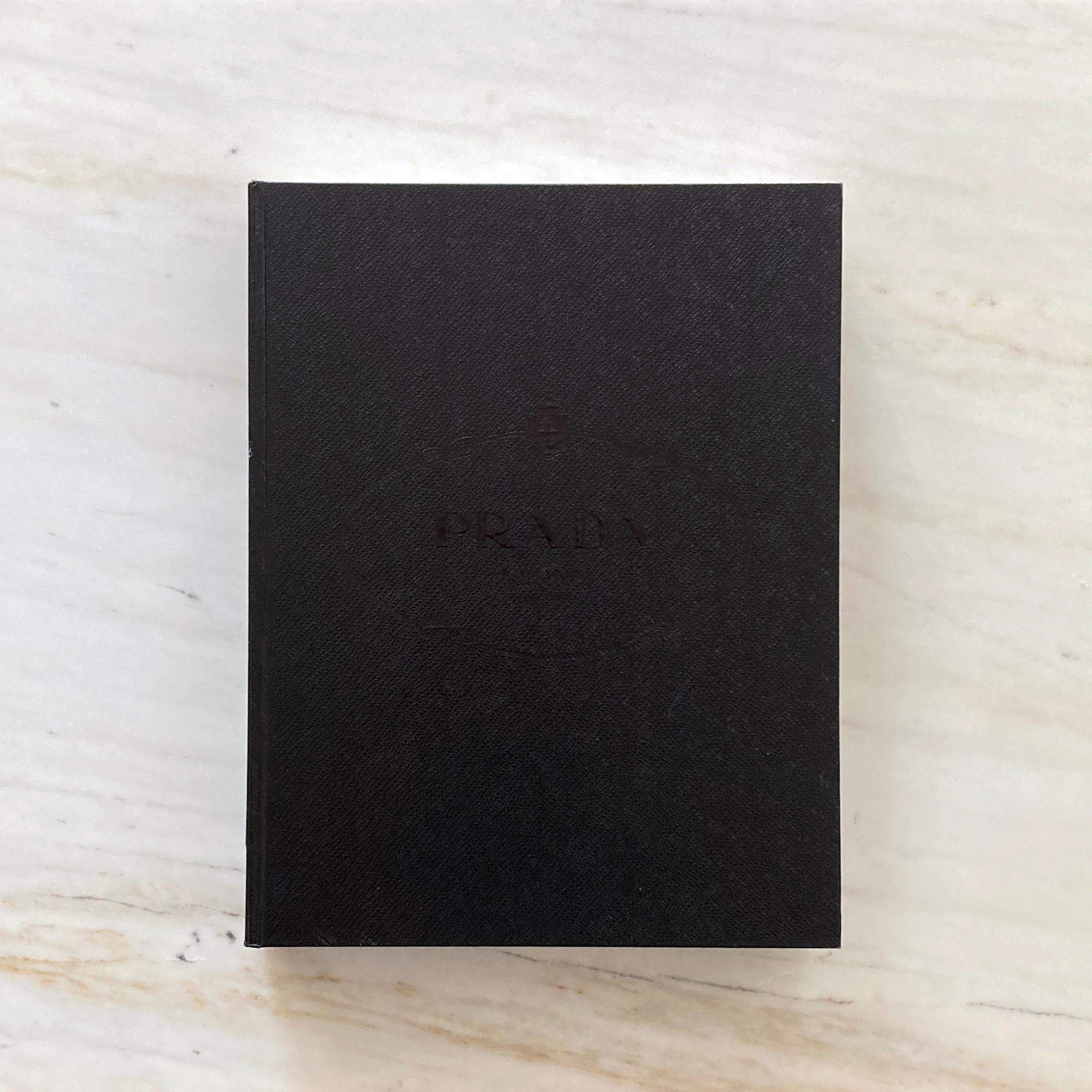 Beautiful Prada Book, saffiano textured faux leather slip case and book cover, this book is filled with hundreds of beautiful photos chronicling Prada’s history, ideas development, production processes, advertising campaigns, and innovative