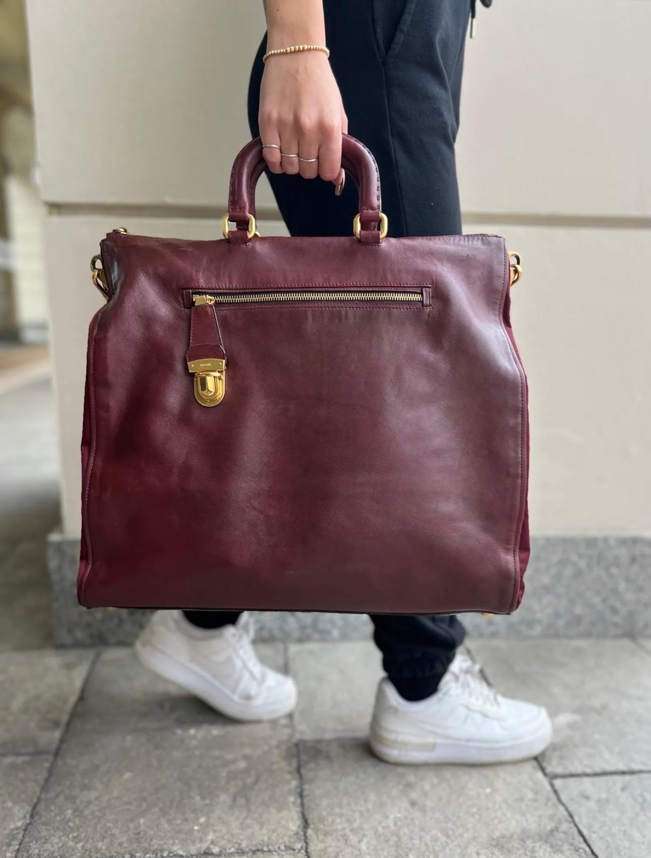 Bag signed Prada, Tote Bag line, made of burgundy leather and fabric with golden hardware.

Equipped with double leather handle and removable shoulder strap to wear the bag by hand or on the shoulder.

Internally lined in burgundy fabric, very roomy