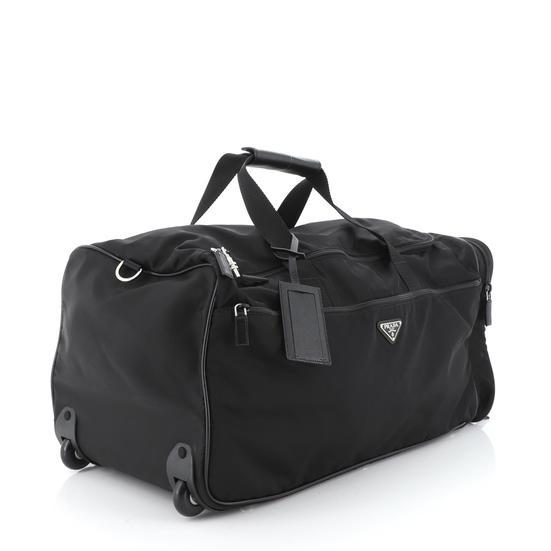 This Prada Boston Trolley Tessuto Large, crafted in black nylon, features a retractable handle, carrying handles, signature inverted triangle Prada logo, exterior zip pockets, two wheels and silver-tone hardware. Its all-around zip closure opens to