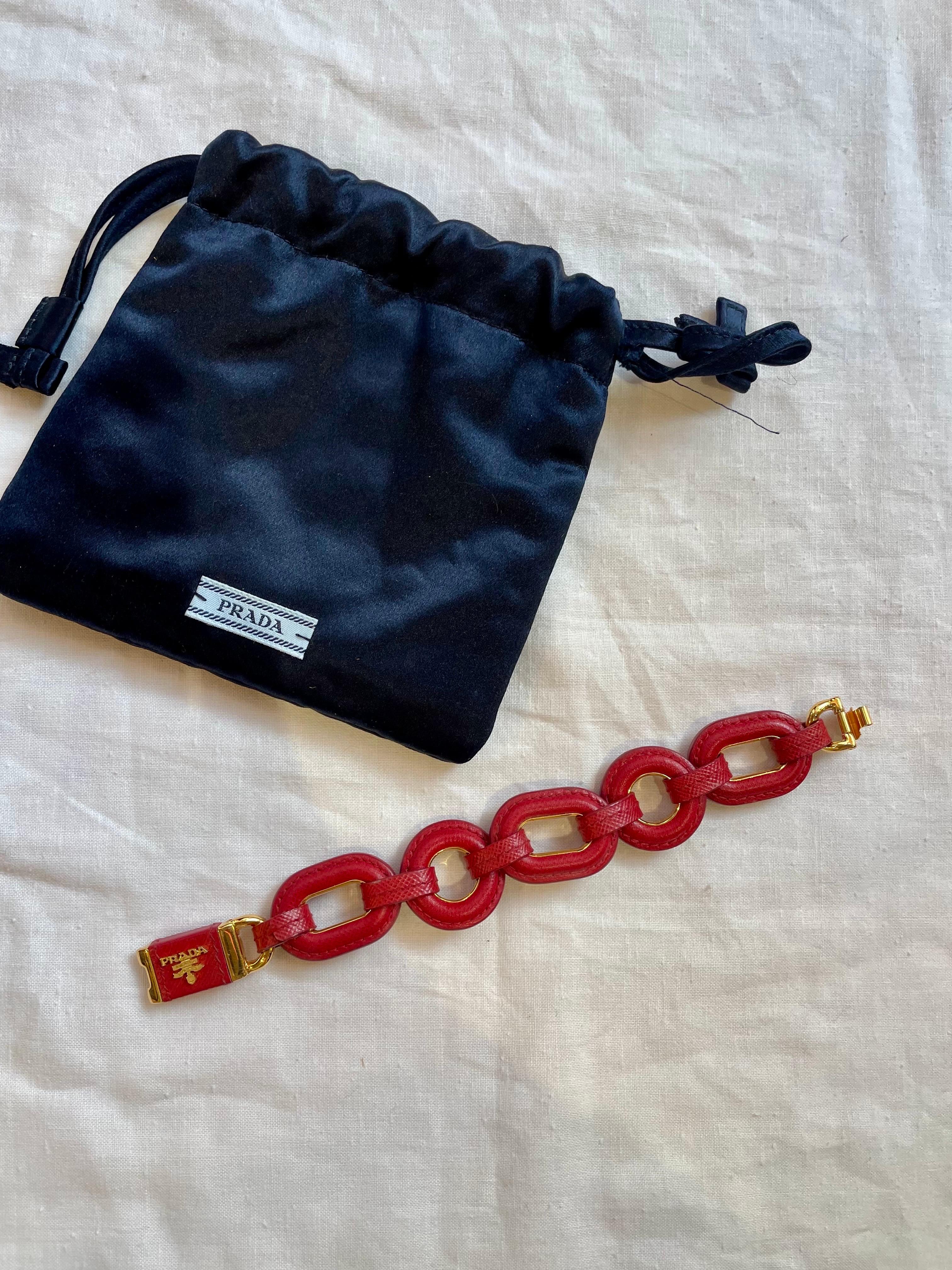 Prada bracelet in dark red saffiano leather with gold hardware. 
It shows some signs of use.
20cm long
3cm tall 
Interlocking hook closure.