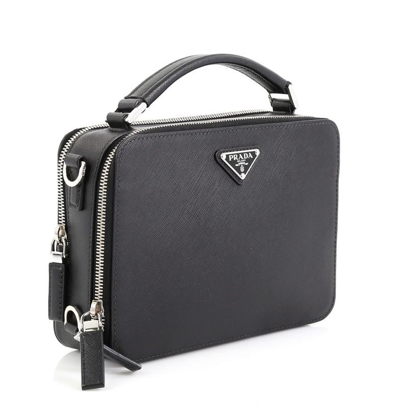 This Prada Brique Crossbody Bag Saffiano Leather East West, crafted in black leather, features a leather top handle, Prada logo and silver-tone hardware. Its zip closures opens to a black fabric interior with zip pocket. 

Estimated Retail Price: