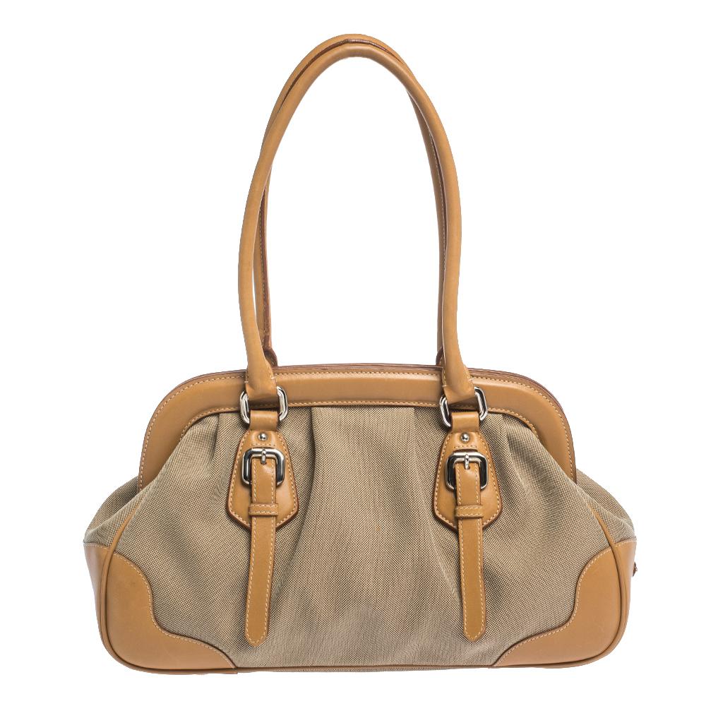 Give your look sophistication with this doctor bag by Prada. This elegantly shaped handbag is crafted from leather and canvas. The exterior is accented with a frame, dual handles, the brand logo in the front buckled straps and silver-tone hardware.