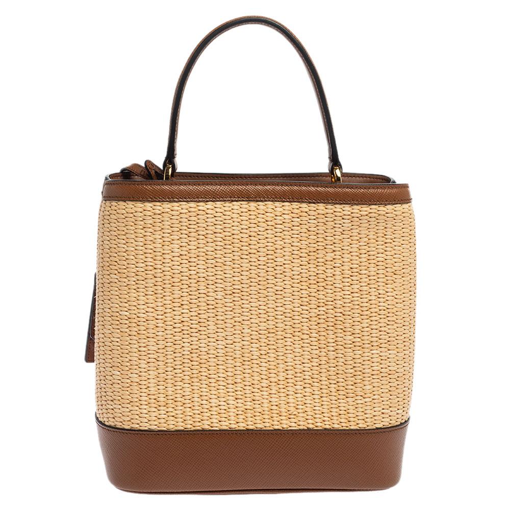 Distinctive in design and style, this Panier bag from Prada definitely deserves to be yours! It has been crafted from brown and beige raffia and leather and features a single top handle and the brand logo at the front. It opens to a spacious