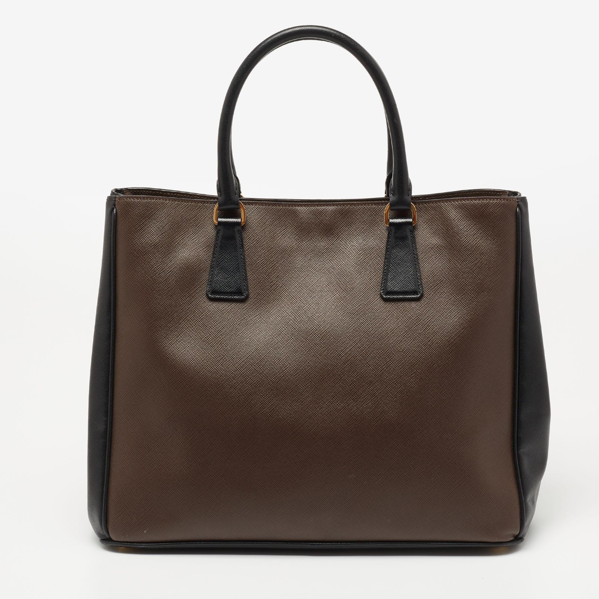 High in appeal and style, this tote is a Prada creation. It has been crafted from leather and shaped to exude class and luxury. The bag comes with two handles, a shoulder strap, and a spacious interior. Protective metal feet and the brand logo on