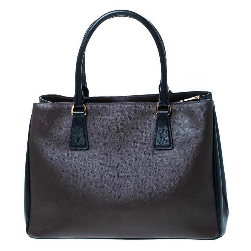 High on style, this tote is an illustration of Prada's impeccable craftsmanship. Made from Saffiano Lux leather, this tote features the shades of brown and black, dual top handles, a detachable shoulder strap, a leather-covered gold-tone key ring