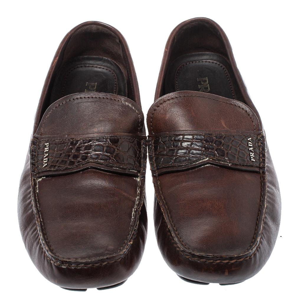 These slip-on loafers from Prada are the ideal pair you'll love having in your closet. They are crafted from leather and crocodile leather in a smart brown color and feature logo detailed straps on the vamps. They are complete with comfortable