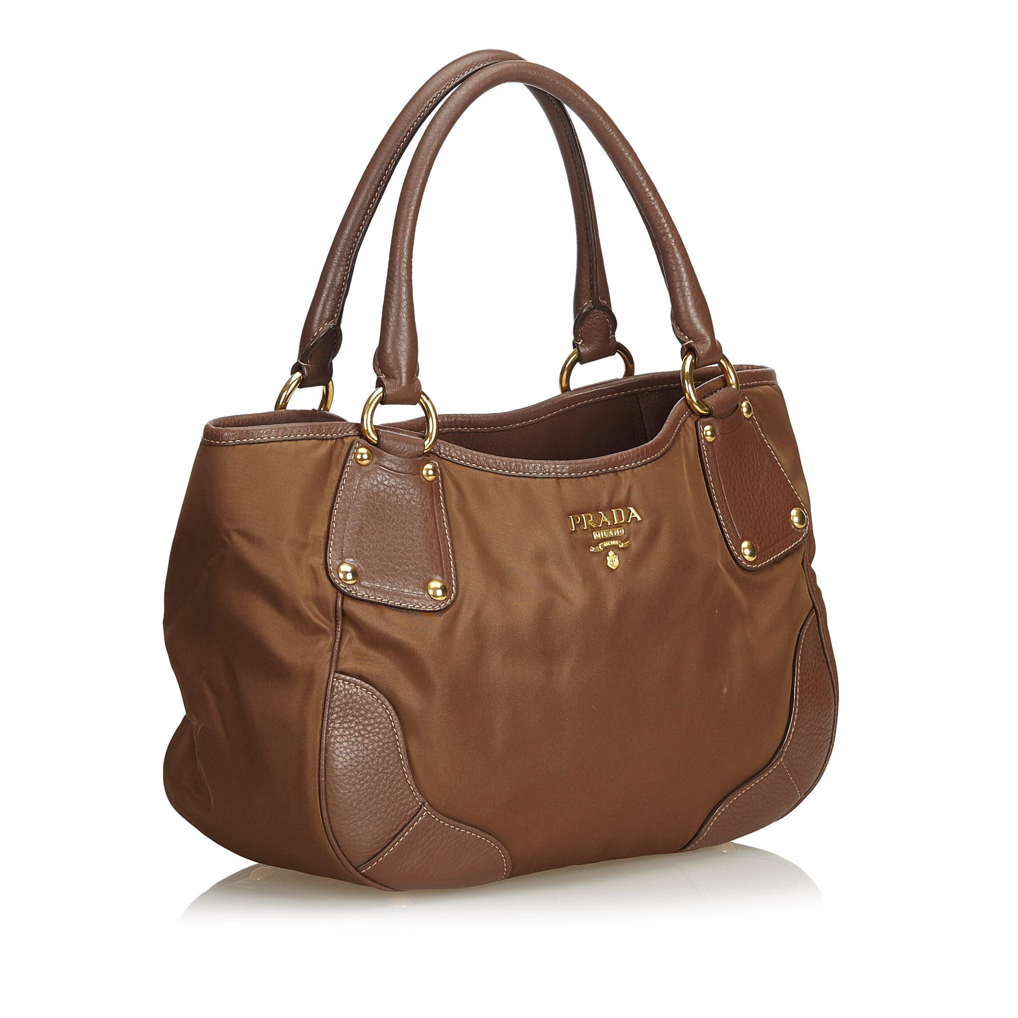 This tote bag features a nylon body with leather trim, rolled leather handles, open top with magnetic closure, and interior zip and slip pocket. It carries as B+ condition rating.

Inclusions: 
This item does not come with