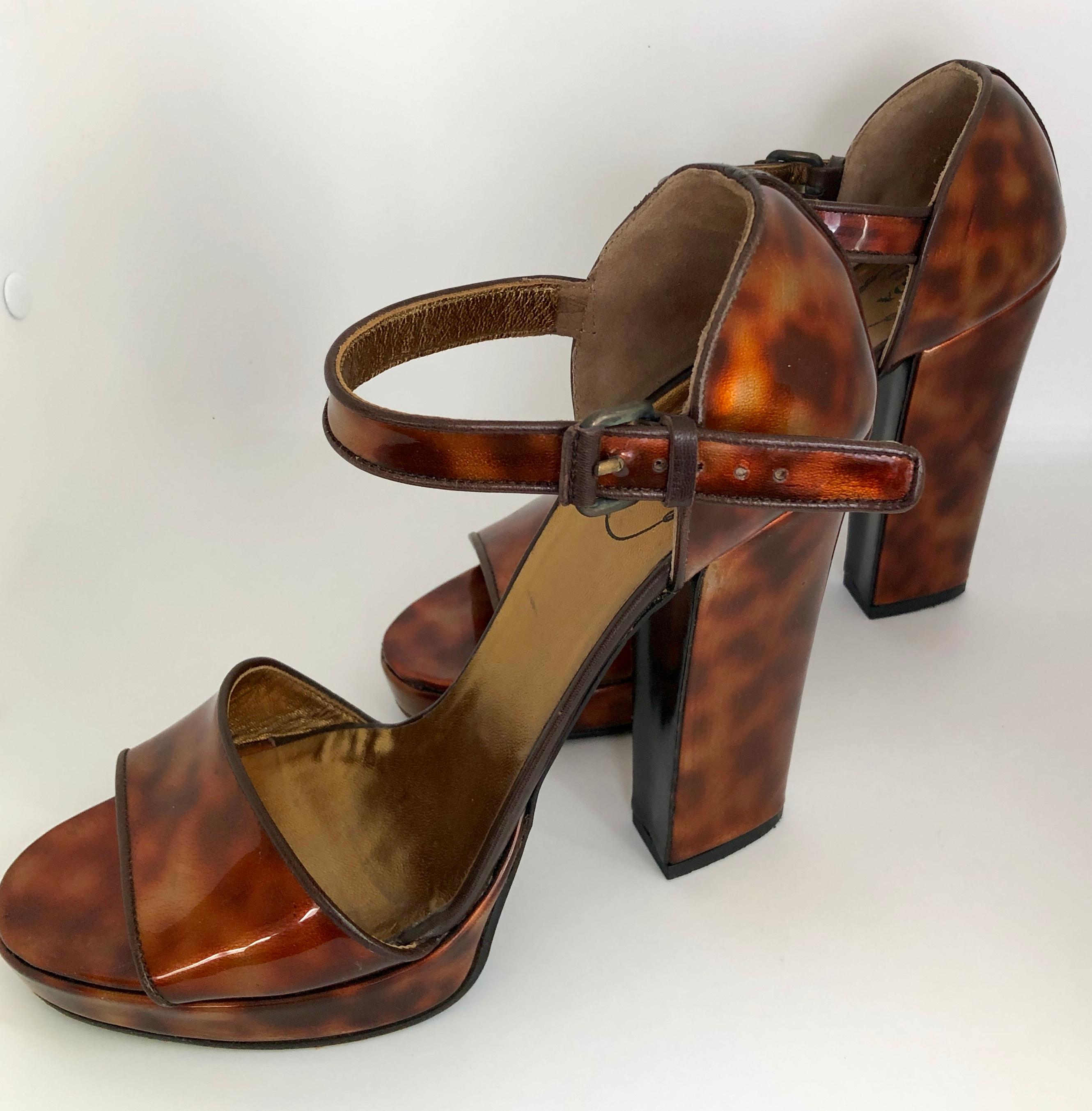 Offered is a pair of Miuccia Prada brown and gold faux tortoiseshell sky high block heel platform ankle strap with buckle sandals.  The heel of the sandal is covered and attached to the ankle strap and buckle with a wide strap over the toe.  