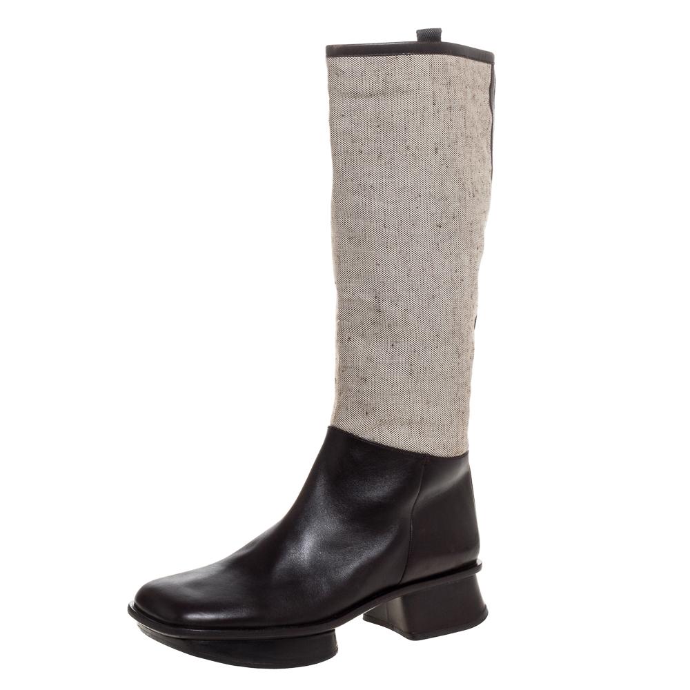 Defined by a modern appeal and impeccable craftsmanship, these knee-high boots from Prada are a must-buy for the fashionable you. These boots are made in canvas as well as leather, decorated with signature details and set on short heels. They are