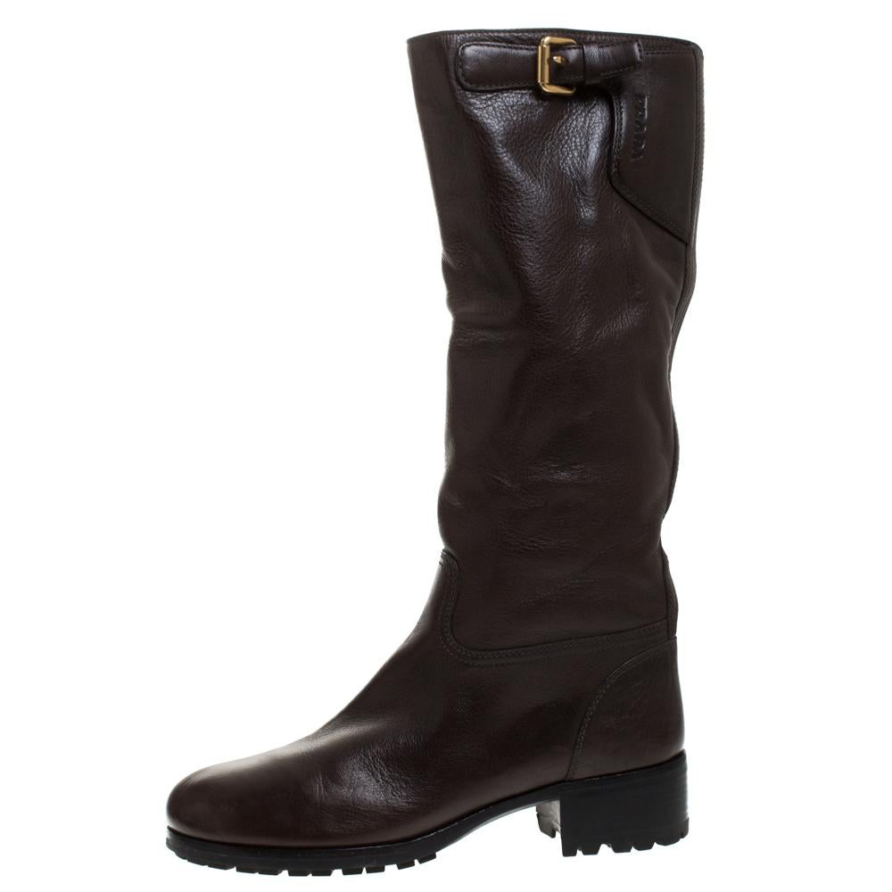 Your winter wardrobe would take an all-new shape by adding these stunning knee-length boots by Prada. These are classic leather boots featuring a brown shade coupled with buckled straps at the top. Adding to the functionality are the round toes and
