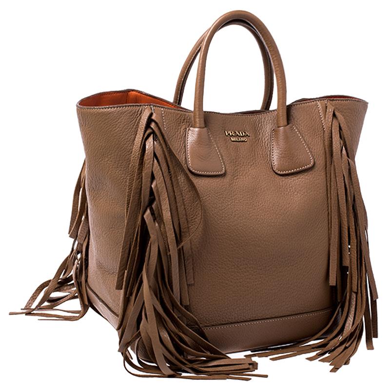 Stunning in appeal and high on style, this tote by Prada will be a valuable addition to your closet. It has been crafted from leather in a lovely brown shade. It comes with two top handles, protective metal feet and a spacious nylon interior secured