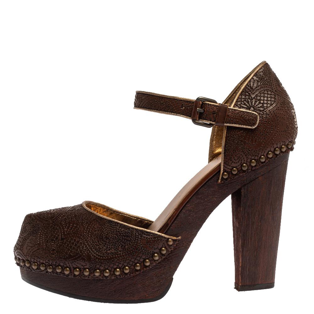 Add vintage charm to your overall look with these sandals from the house of Prada. Crafted in Italy, they are made from intricately embroidered leather in a brown shade and outlined with metal studs. These sandals have 11.5 cm wooden block heels
