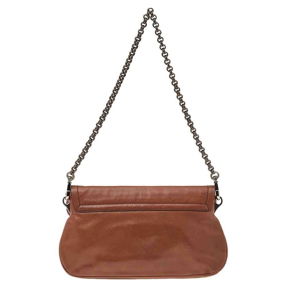 Designed by the House of Prada, this shoulder bag exudes nothing but charm and luxury. It has been made using brown leather and embellished with a silver-toned lock closure on the front. Its shape is held beautifully by a sturdy chain strap. Let